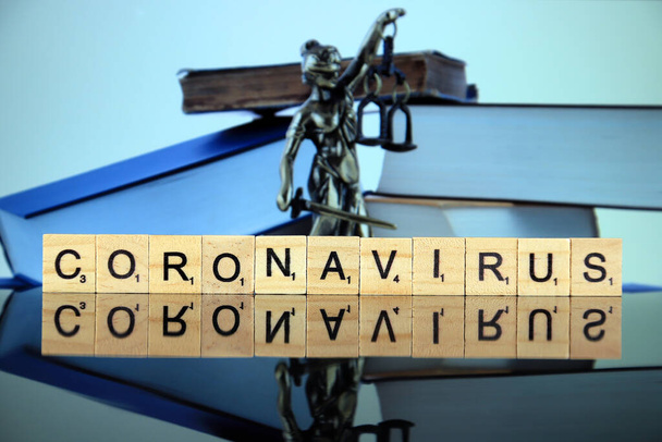 WROCLAW, POLSKA - 30 marca 2020: Słowo CORONAVIRUS wykonane z liter drewnianych oraz symbol prawa i sprawiedliwości w tle. Światowa choroba koronawirusowa (COVID-19) 2020. - Zdjęcie, obraz