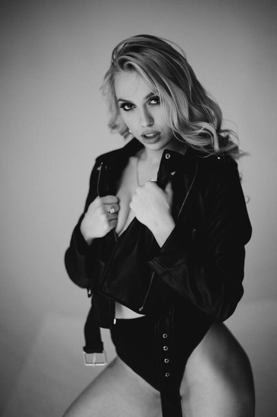 In body. Monochrome portrait of a blond beautiful young woman. Fashion model with a lovely shapely figure posing in lingerie and a lizard jacket. - Foto, afbeelding