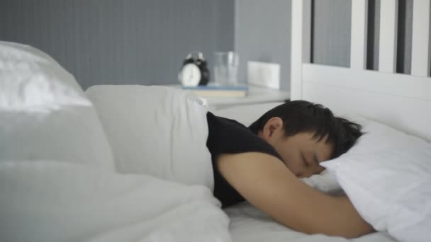 Primer plano de joven asiático hombre acostado y durmiendo en la cama en casa
. - Imágenes, Vídeo