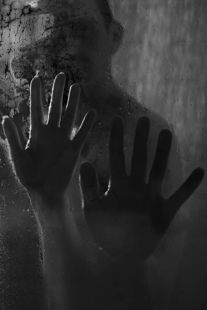 Ręce mężczyzny i kobiety na mokrym szkle pod prysznicem. Zbliżenie. Czarno-białe fotografie. - Zdjęcie, obraz