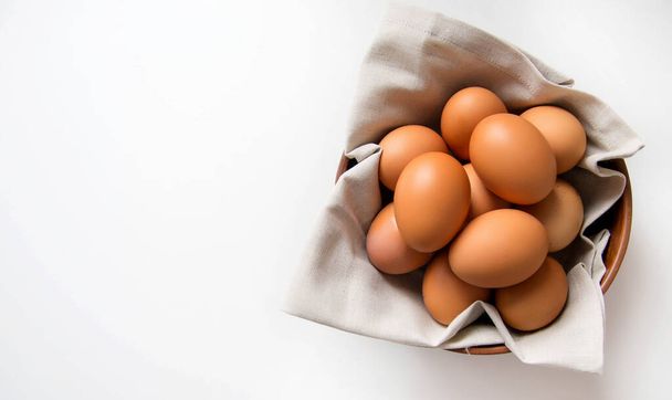 Chicken eggs in a plate with a linen napkin on a white table. copy space. - Фото, зображення