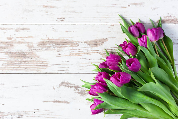 Kytice jarních fialových tulipánů na bílém dřevěném pozadí horní pohled. Jarní pozadí. Pozdrav na dovolenou. Kopírovat prostor. - Fotografie, Obrázek