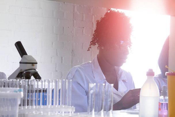 Test tesisi. Genç Afrikalı kadın bilim adamı ya da tıp teknisyeni, pozitif profesyonel kadın, yeni koronavirüs için idrar, kan ve nükleik asitlerin test edilmesi üzerinde çalışıyor.. - Fotoğraf, Görsel