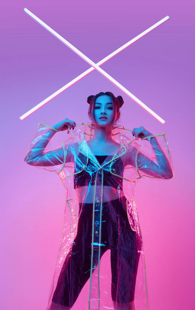 Portrait of elegant beautiful Asian woman in a fashionable raincoat around colourful bright neon uv lights posing in studio - Fotoğraf, Görsel