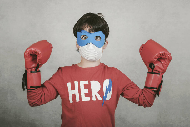 Coronavirus.child dragen masker voor coronavirus verkleed als een superheld over grijze achtergrond - Foto, afbeelding
