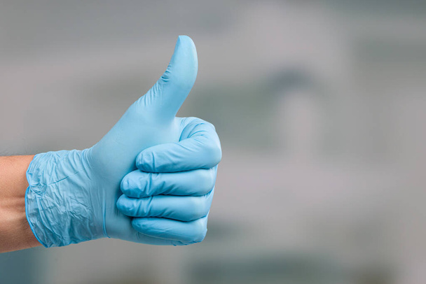 main avec gant médical montre pouces en face d'une salle de clinique
 - Photo, image