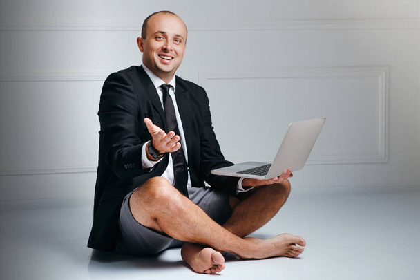 Бизнесмен, сидящий на полу с ноутбуком в офисе
 - Фото, изображение