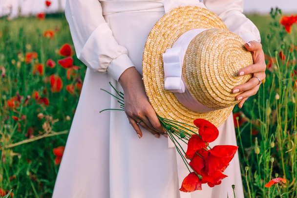 closeup bouquet of red poppies and boater in the hands of a girl in a white dress. - Fotografie, Obrázek