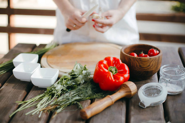 Женские руки рубят чеснок на деревянной доске. Приготовление здоровой пищи для пикника
 - Фото, изображение