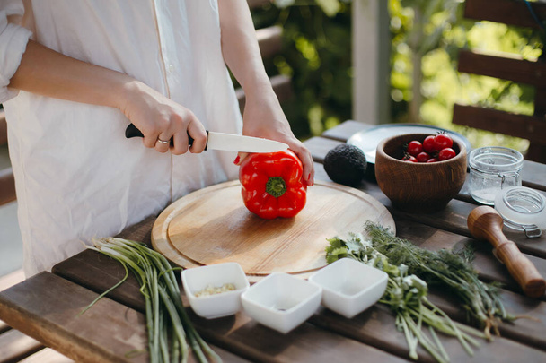 Manos de mujer cortando pimiento rojo en plato de madera. Comida vegetariana saludable
 - Foto, imagen