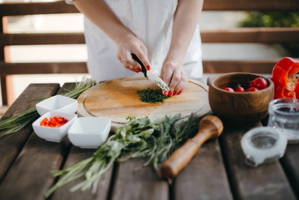 Ženské ruce sekají kopr o dřevěný talíř. Výroba guacamole - Fotografie, Obrázek
