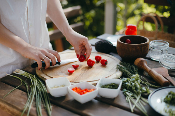 Жіночі руки вирізають вишневі помідори на дерев'яній тарілці. Виготовлення гуакамоле
 - Фото, зображення