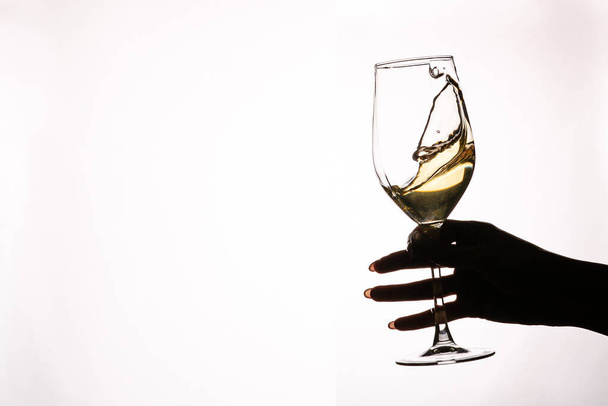 Female hand holding glass with white wine toasting isolated on a white background - Zdjęcie, obraz