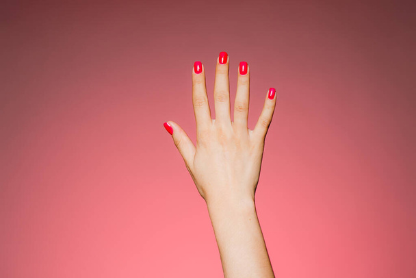 Рука жінки з яскравим манікюром ізольована на рожевому фоні
 - Фото, зображення