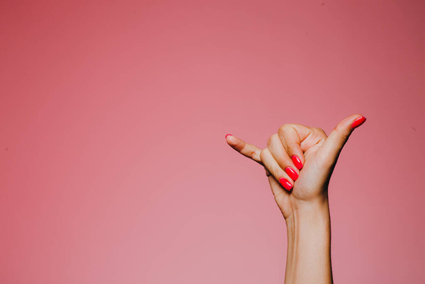 Vrouw handen met heldere manicure geïsoleerd op roze achtergrond bel me teken - Foto, afbeelding