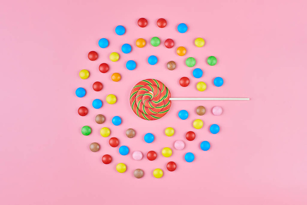 ピンクの背景に甘いロリポップとキャンディ、コピースペース。子供の頃のコンセプトでカラフルなお菓子への愛 - 写真・画像