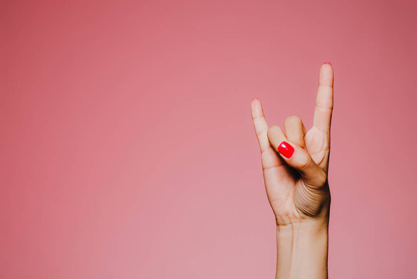 Les mains de la femme avec manucure lumineuse isolé sur fond rose signe métallique hevy
 - Photo, image