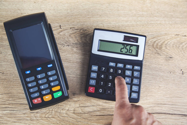 muž ruční platební terminál s kalkulačkou na stole - Fotografie, Obrázek