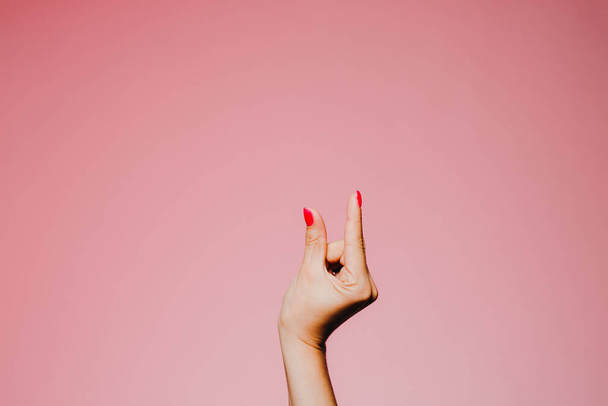 vrouwenhanden met heldere manicure geïsoleerd op roze achtergrond klein formaat gebaar - Foto, afbeelding