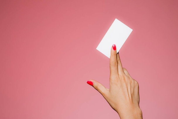Női kéz tartja üres névjegykártya elszigetelt rózsaszín - Fotó, kép