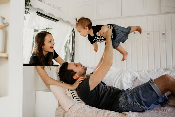 husband and wife play with their child, dad, mom and daughter, a woman holds her daughter by the hand, very funny and beautiful family, beautiful interior, motor home, a family who travels - 写真・画像