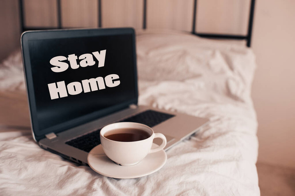 Cup of coffee on laptop with stay home text in bed closeup. Good morning. Breakfast time.  - Fotografie, Obrázek