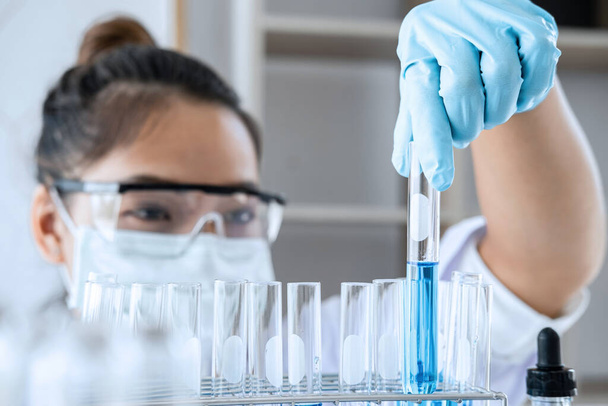 Badania laboratoryjne biochemii, Chemik analizuje próbki w laboratorium ze sprzętem i eksperymentami naukowymi szklanymi zawierającymi płyn chemiczny. - Zdjęcie, obraz