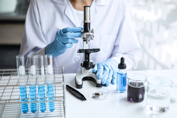 Biochemistry laboratory research, Chemist is analyzing sample in laboratory with Microscope equipment and science experiments glassware containing chemical liquid. - Foto, immagini
