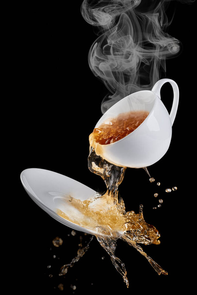 The coffee from the mug splashes out on the saucer, splashes of coffee flying in different directions. - Zdjęcie, obraz