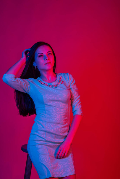 High Fashion model woman in colorful bright lights posing in studio, portrait of beautiful sexy girl. Over colourful vivid background. Brunette girl in a blue dress. Long straight hair - Φωτογραφία, εικόνα