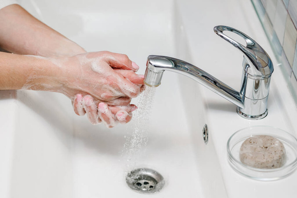 Washing hands. Coronavirus prevention. Wash hands with antibacterial soap and warm running water rubbing nails and fingers in sink. Epidemic Covid-19. Prevention of flu disease. - Foto, afbeelding
