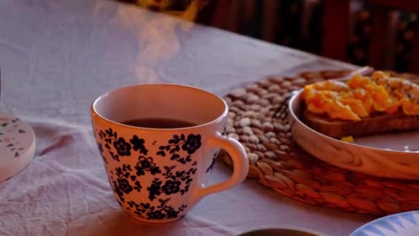 forró gőzölgő tea mellett reggeli tányér, meleg hangulatos otthon - Felvétel, videó