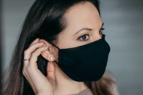 コロナウイルスの流行のために医療マスクの家でブルネットの女性は、ウイルスを止める方法を考えています.  - 写真・画像