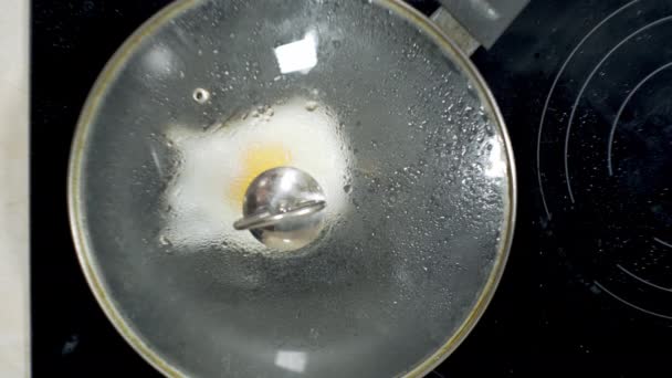 fried eggs cooked in a frying pan at home on the stove in sunflower oil - Filmati, video