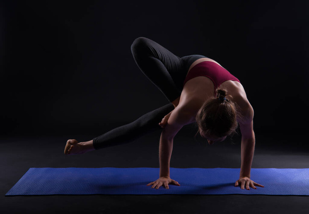 Genç sporcu kadın siyah arka planda yoga yapıyor. - Fotoğraf, Görsel