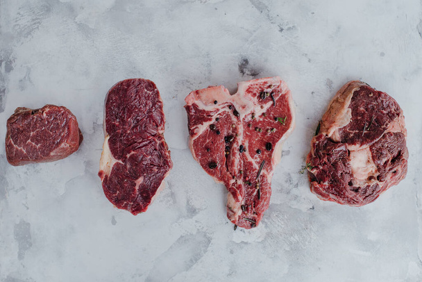 Différents types de viande crue pour steaks, T-bone, côtelette, filet, surlonge sur un bureau en marbre
. - Photo, image