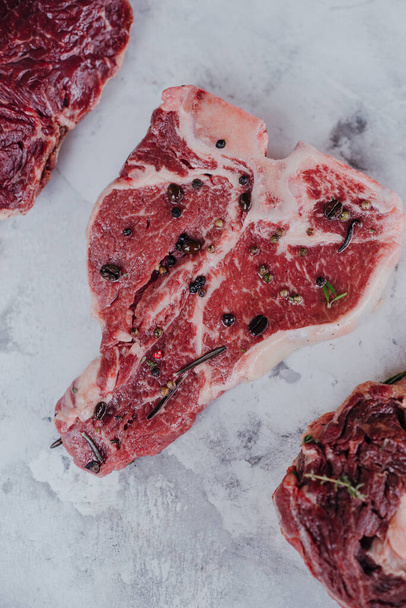 T-Bone, Steak. Verschiedene Arten von rohem Fleisch für Steaks, T-bone, Ribeye, Filet, Roastbeef auf einem Marmortisch. - Foto, Bild