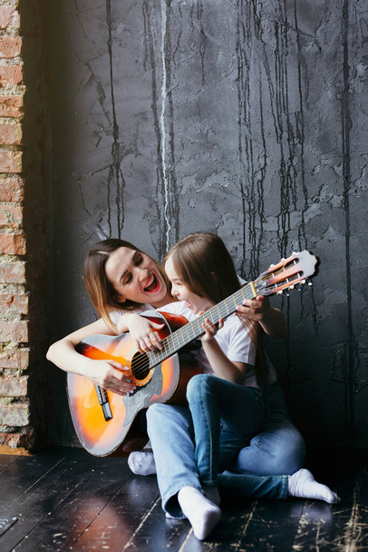 Красива мати і дочка вчаться грати на гітарі під час карантину та ізоляції
 - Фото, зображення