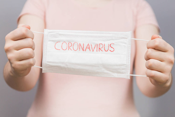 Neuartige Coronavirus - Chirurgische Maske Schutzmaske mit CORONAVIRUS Text. Ausbruch des chinesischen Coronavirus. Maske in Händen Frau - Foto, Bild