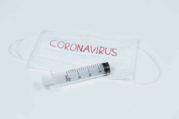 Mask with the inscription coronavirus and pills, syringes. Pandemic disease - Foto, afbeelding