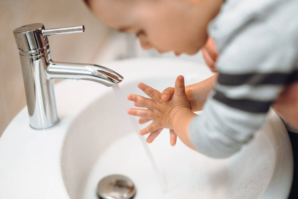 Biały ojciec myjący, czyszczący i oczyszczający małe rączki mydłem i wodą z kranu. Ojciec i dziecko myją ręce - Zdjęcie, obraz