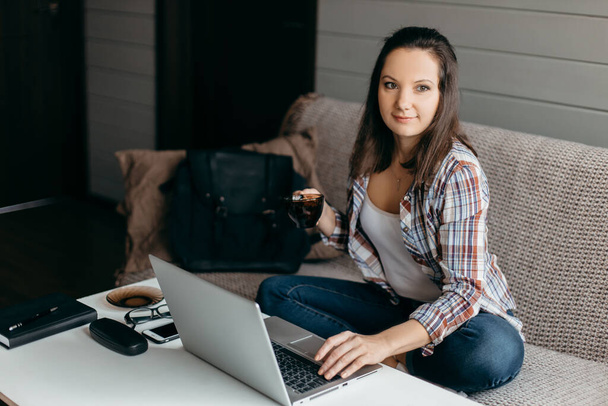 miła piękna brunetka kobieta praca w notatniku usiąść na kanapie w domu - sprawdź sklepy internetowe dla cyber sprzedaży - praca w domu koncepcja - Zdjęcie, obraz