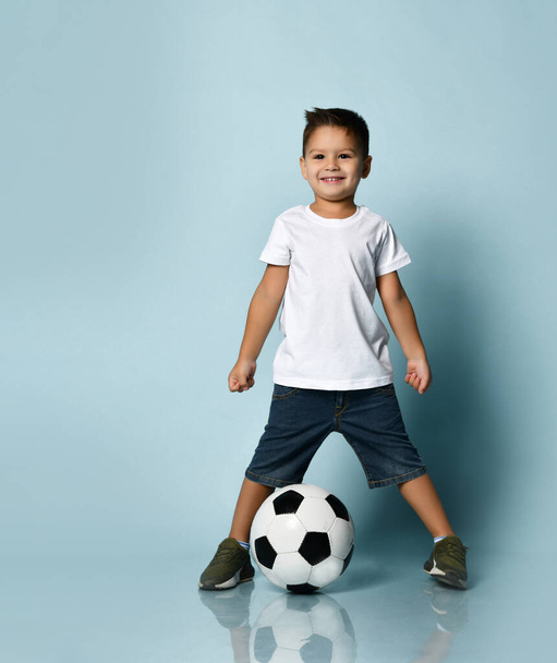 Cute boy playing football, happy child, young male teen goalkeeper enjoying sport game, holding ball, isolated portrait of a preteen smiling and having fun - Valokuva, kuva