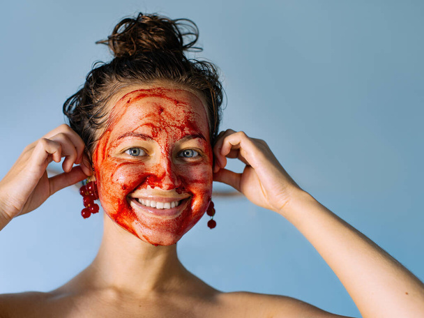 Młoda dziewczyna z orzeźwiającą maską owocową z czerwonej porzeczki na twarzy.  - Zdjęcie, obraz