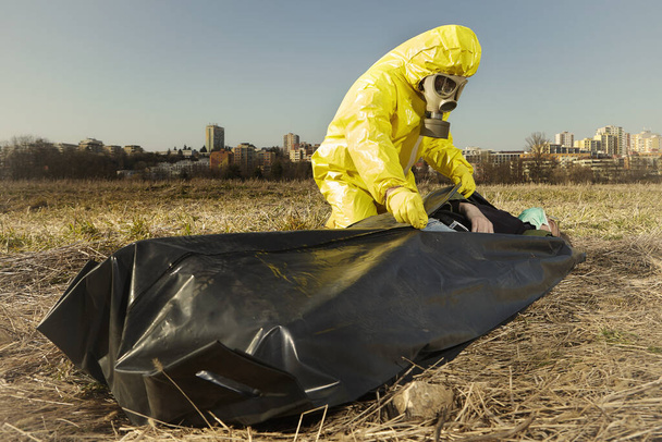 Man in protection suits preparing victim of disease for transport - Fotografie, Obrázek