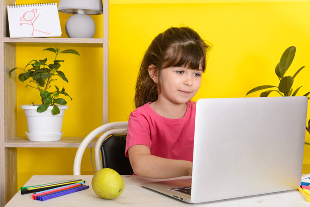 Інтернет-школа. Дівчинка використовує ноутбук. Дистанційне навчання або дистанційне навчання. Дитяча дівчинка навчається онлайн у своїй вітальні. Ковід-19 коронавірус
. - Фото, зображення