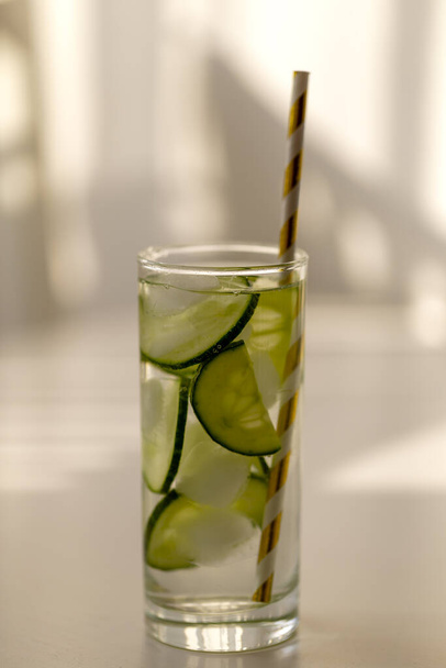 Zelfgemaakte limonade met de smaak van komkommers, die in een glas zitten. Er zit een rietje in het glas.. - Foto, afbeelding
