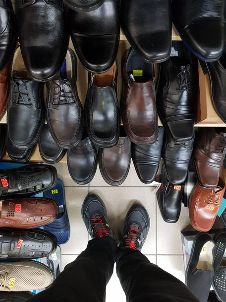 Młody mężczyzna wybiera nowe buty w sklepie - Zdjęcie, obraz