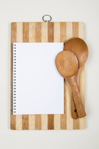 Schöpfkelle aus Holz mit leerem Notizbuch auf neutralem Hintergrund - Foto, Bild