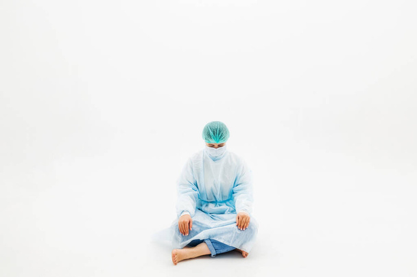 Nainen suojapuvuissa ja kasvonaamioissa. Mies istuu valkoisella taustalla suojaavissa lääketieteellisissä takeissa, lakeissa ja naamioissa. Influenssaviruspandemian tragedia
 - Valokuva, kuva